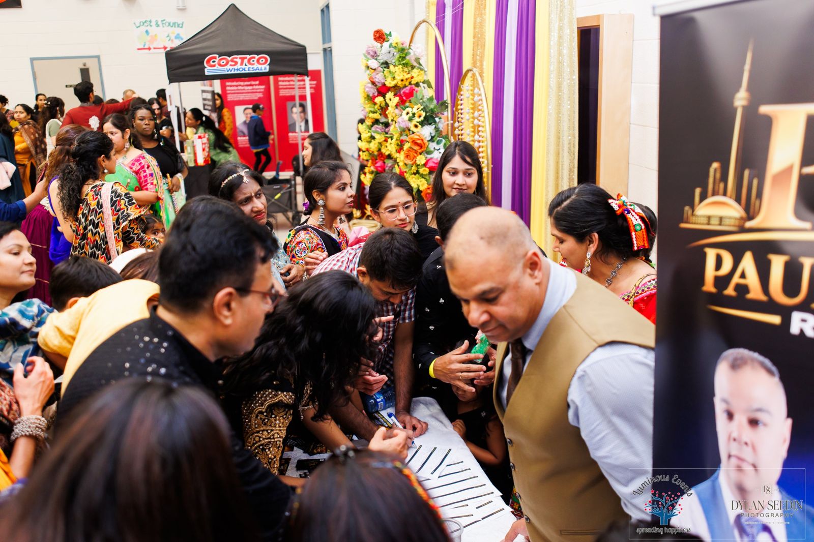 A crowd of guests gathered around a sponsor and vendor table